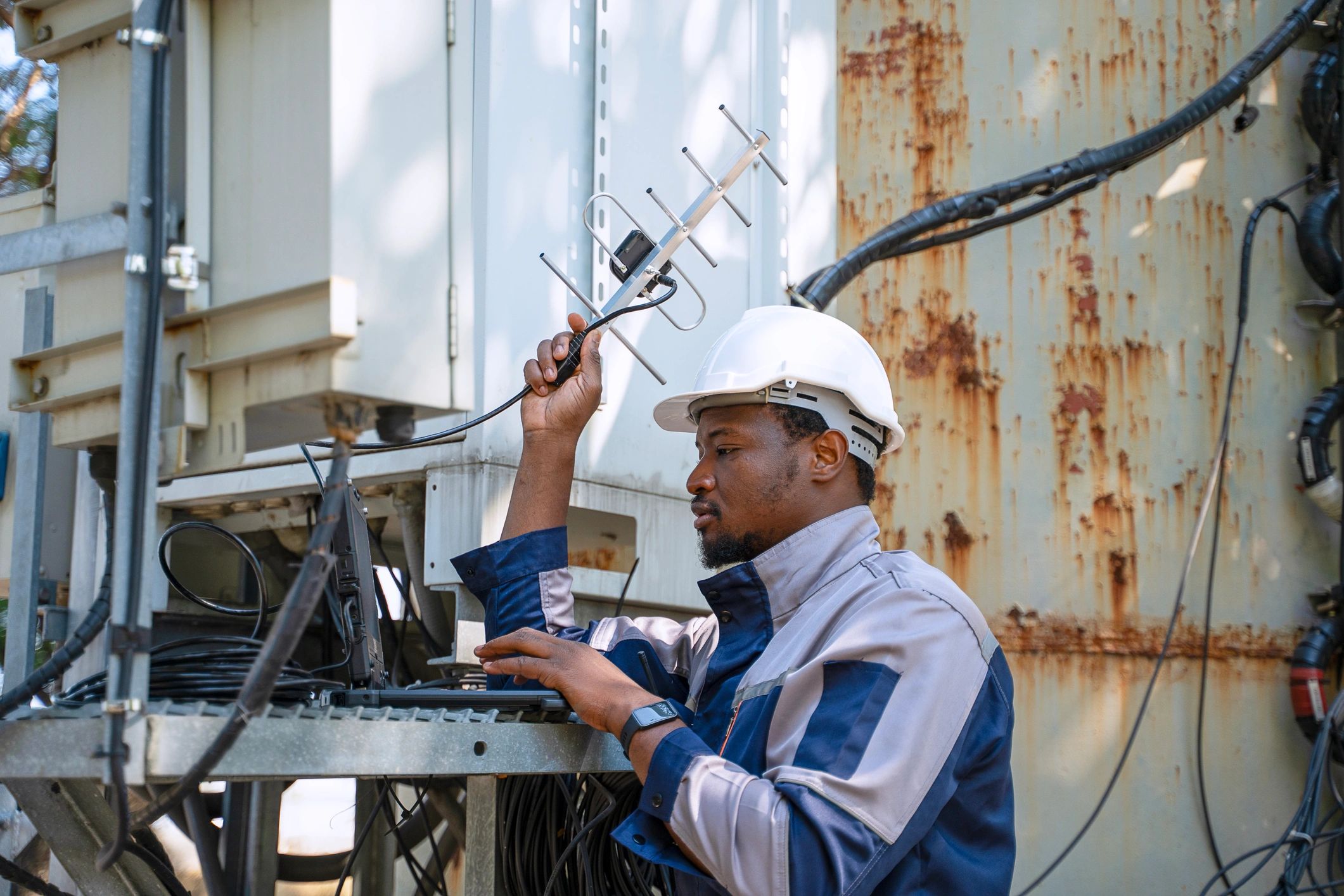Engineer inspecting communication signal equipment with a laptop